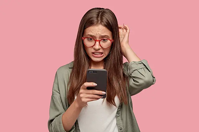 Mulher olha com preocupação para a tela de seu celular.