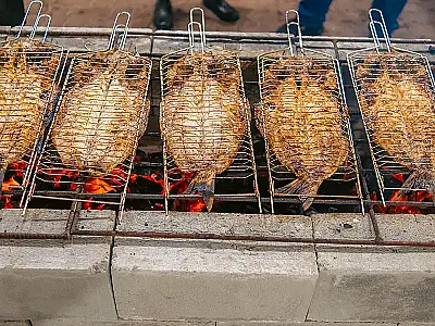 Preparação da tradicional tainha assada na brasa durante a 49ª edição do evento gastronômico do litoral.